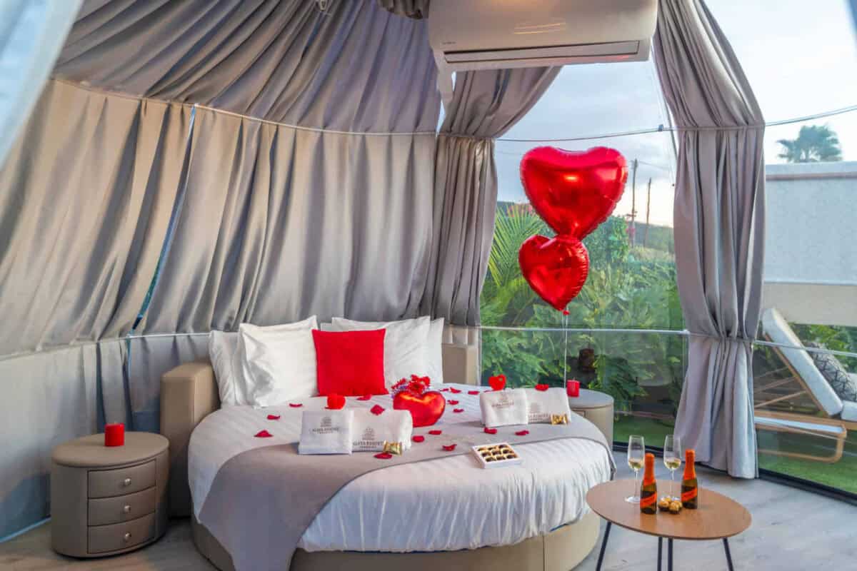 Suite burbuja con decoración romántica: pétalos de rosa, globos de corazón y cava